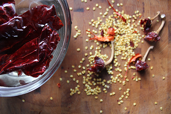 dried chiles in bowl of water next to discarded seeds