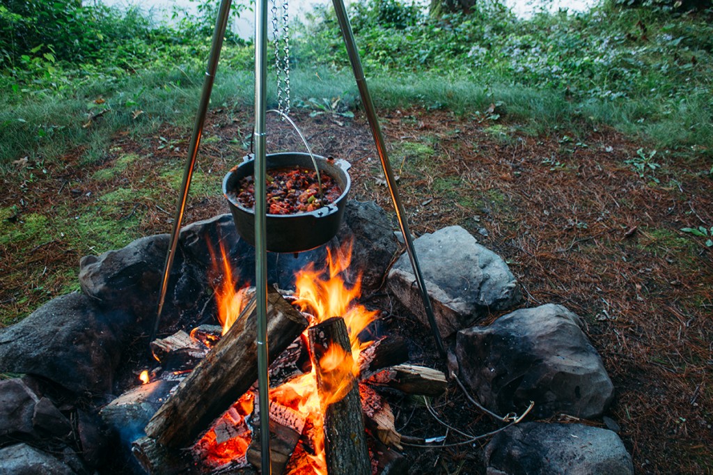 campfire with pot of three bean chili suspended over top