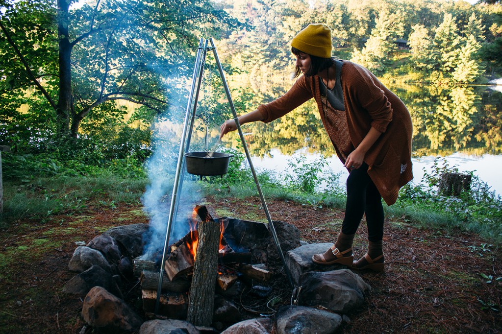 woman stirring pot of three bean chili over campfire