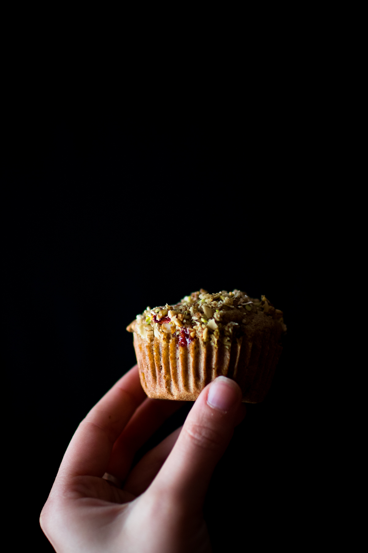 woman's hand holding a strawberry rhubarb muffin