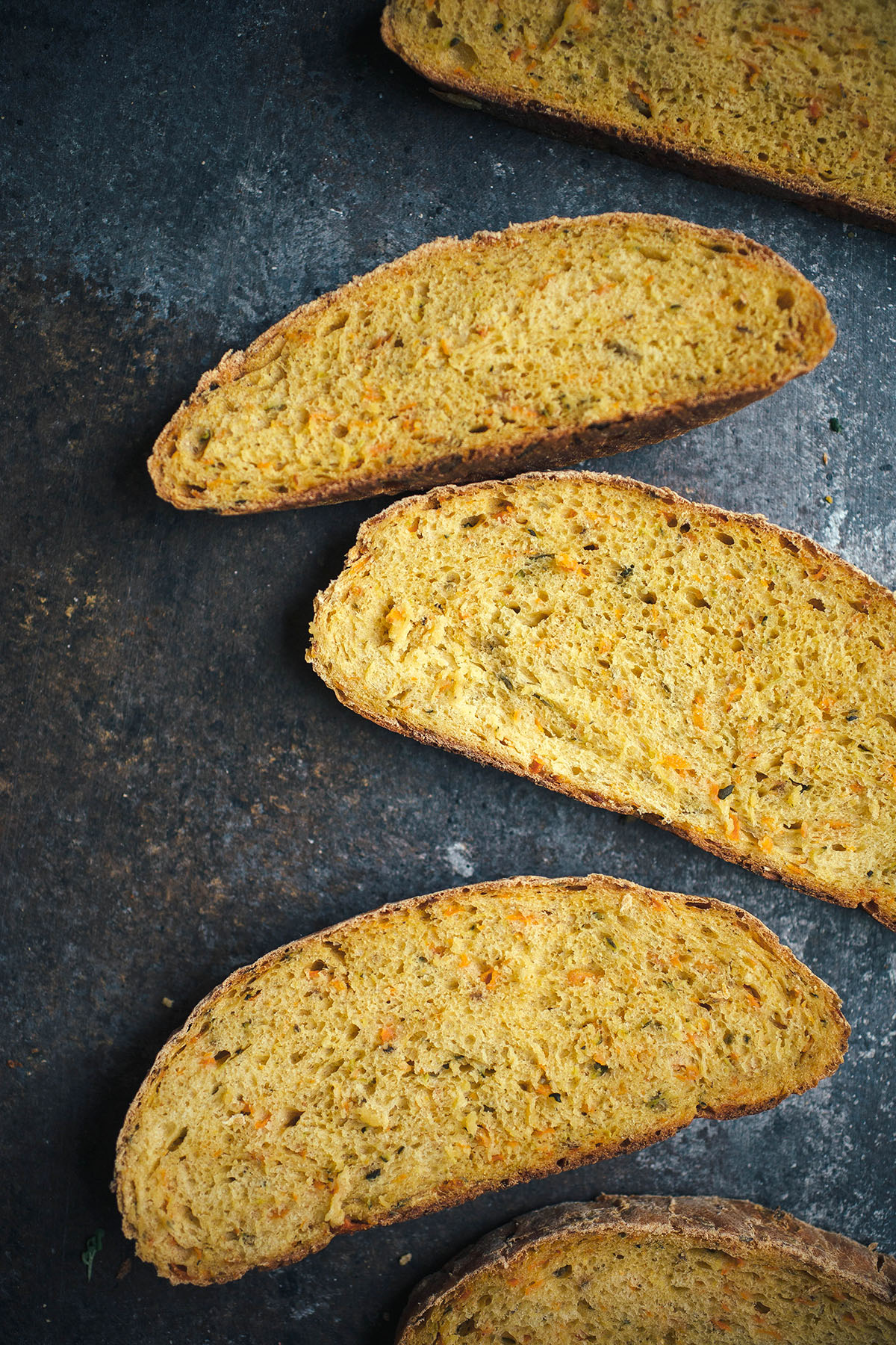 three slices of veggie bread on dark surface