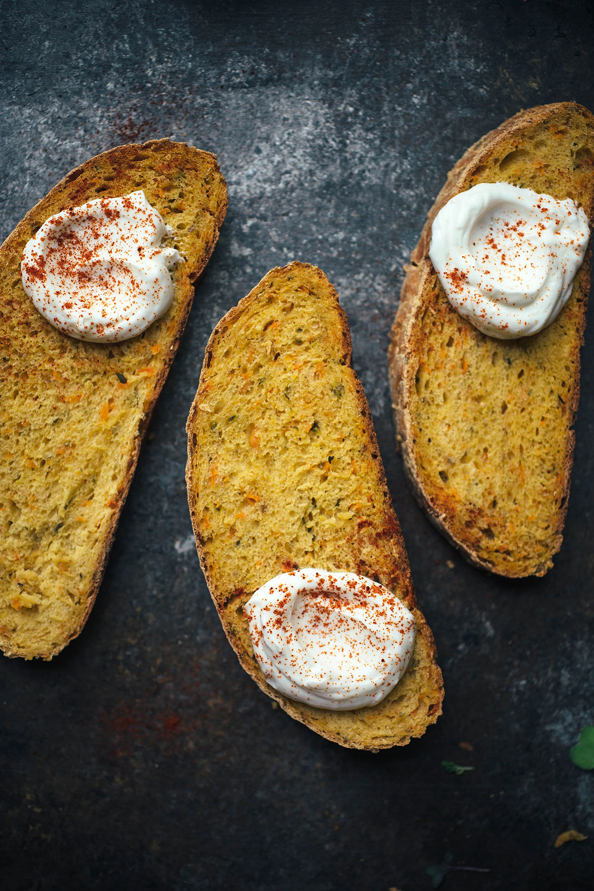 three slices of vegetable bread topped with yogurt and paprika