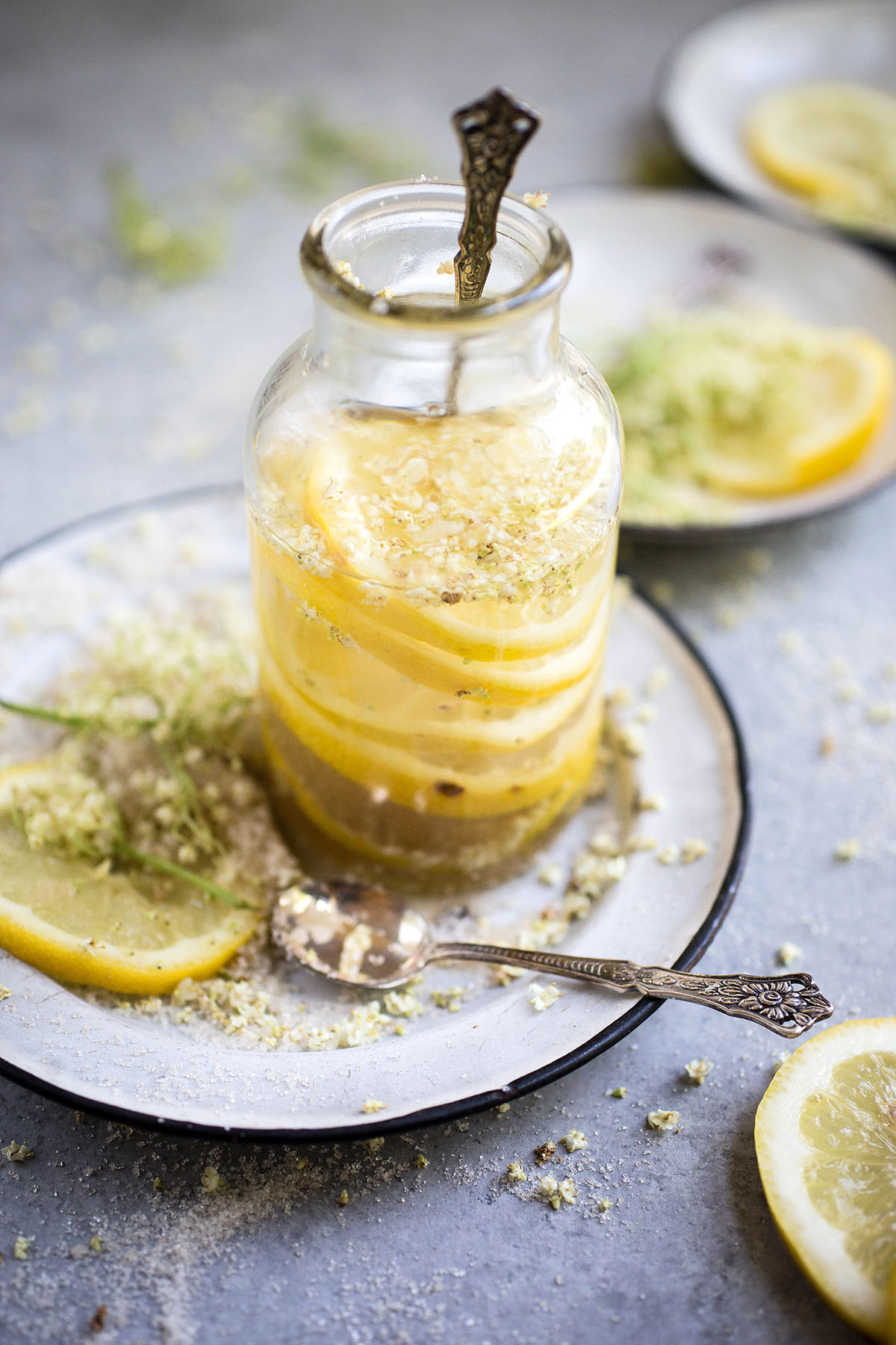 glass of elderflower lemonade garnished with elderflower blossoms and lemon slices