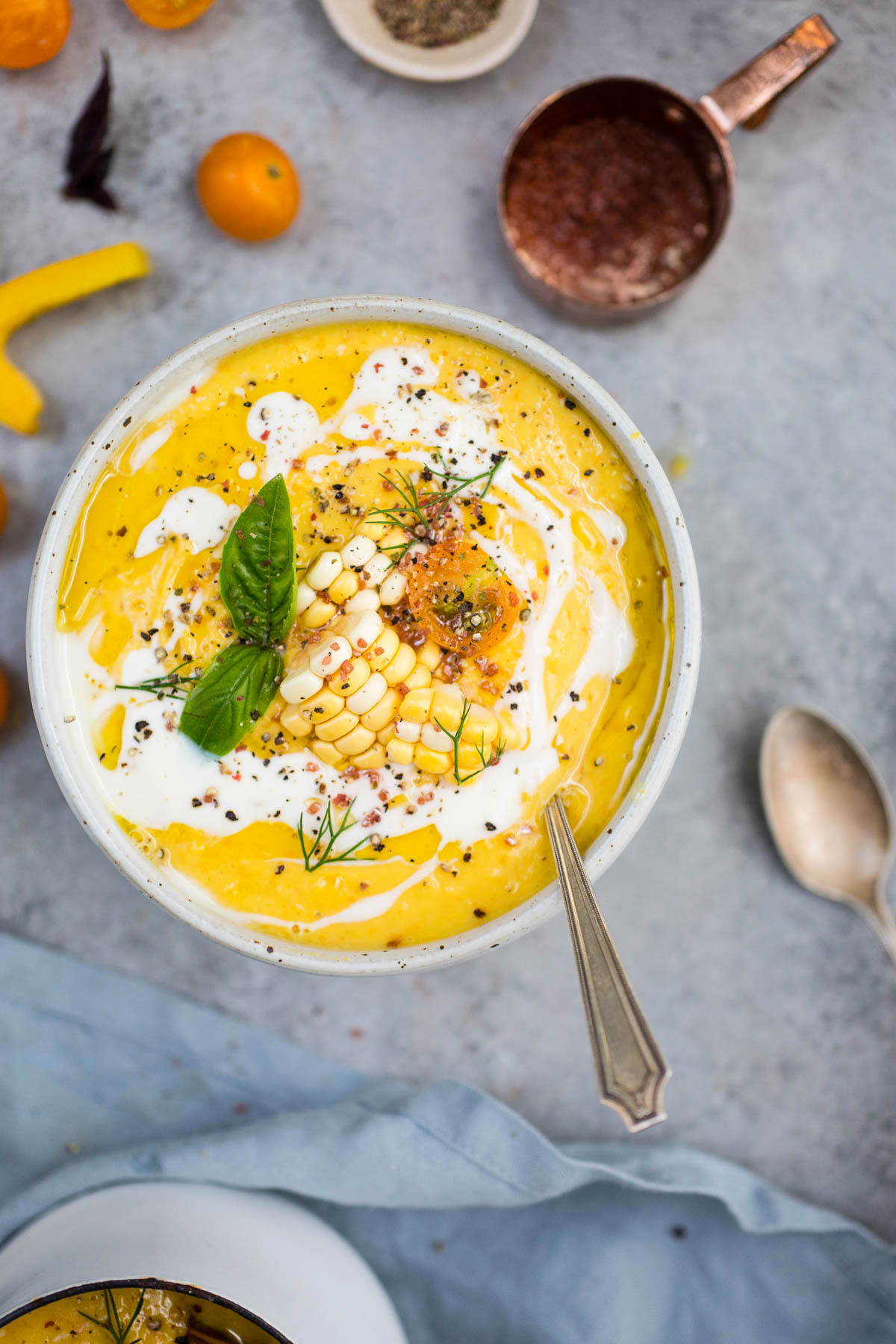 bowl of sweet corn and tomato gazpacho garnished with herbs, sweet corn, and tomatoes 