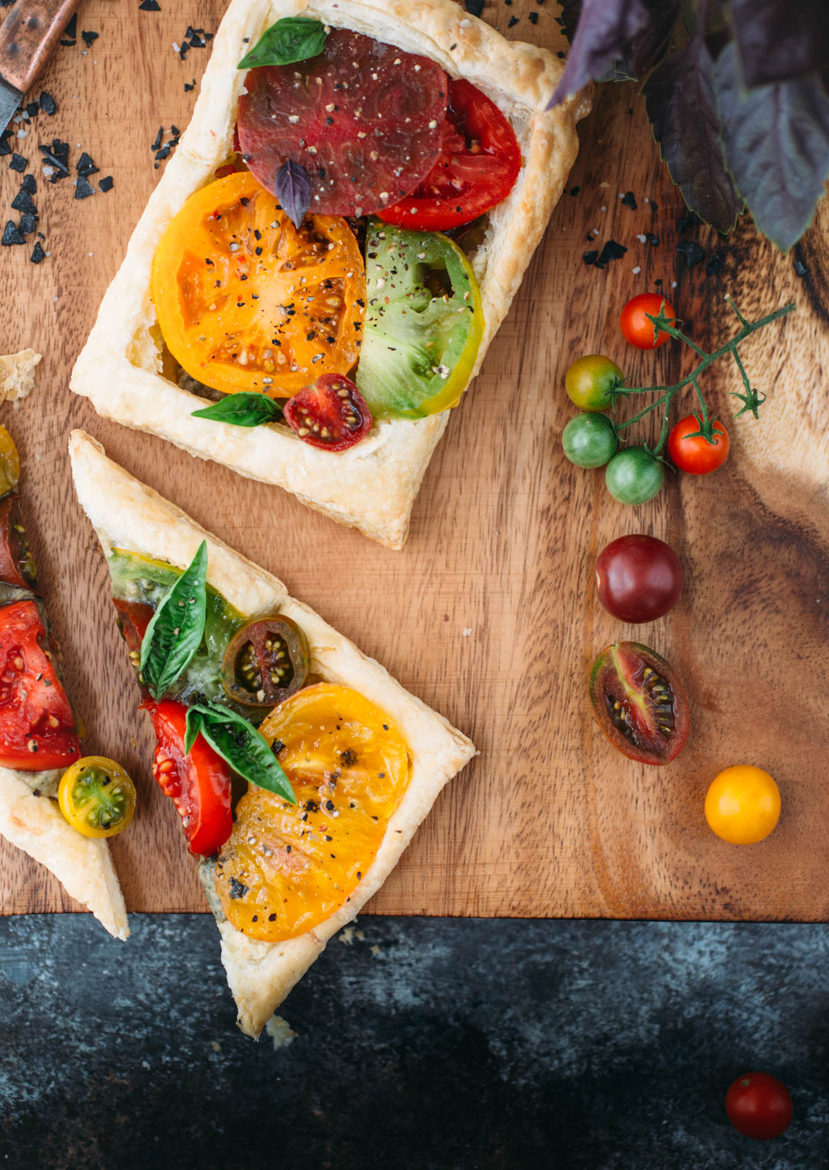 two puff pastry tomato tarts on wood cutting board 