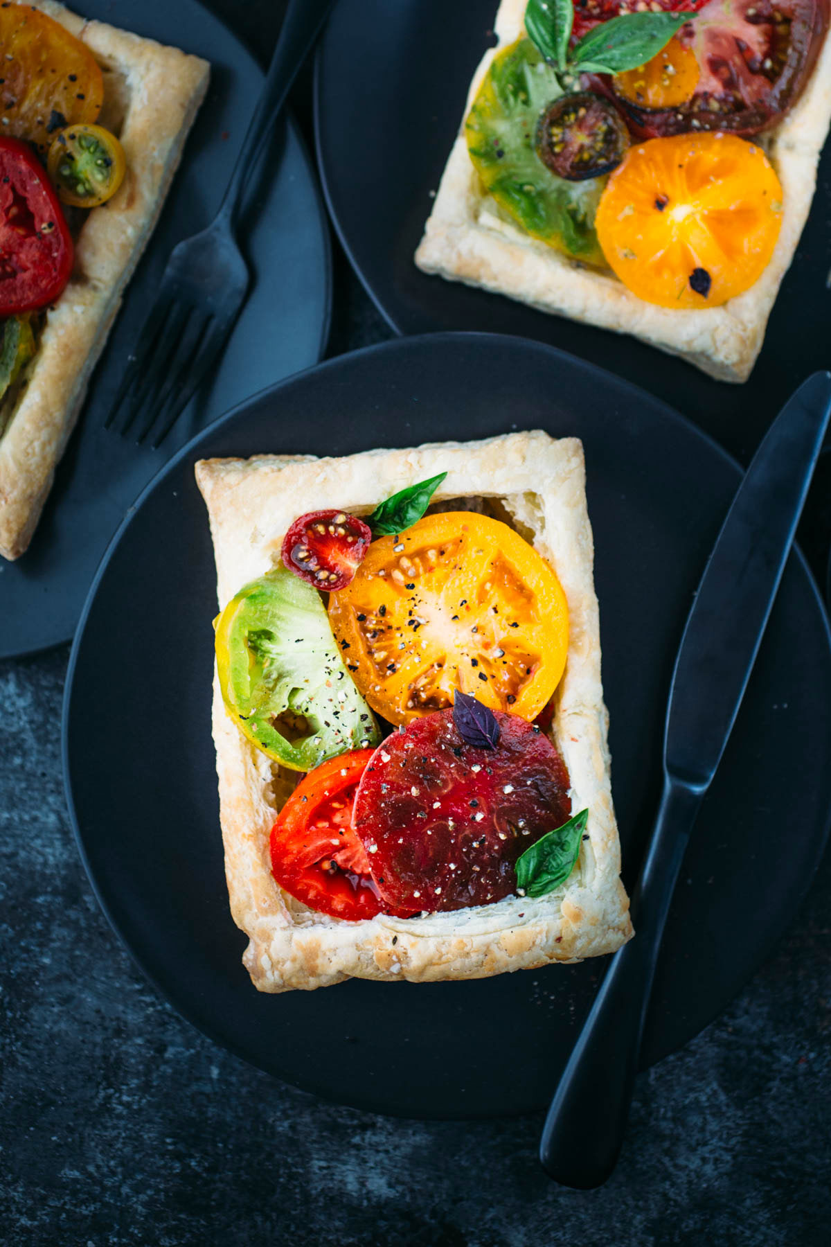 puff pastry tomato tart on dark plate with knife