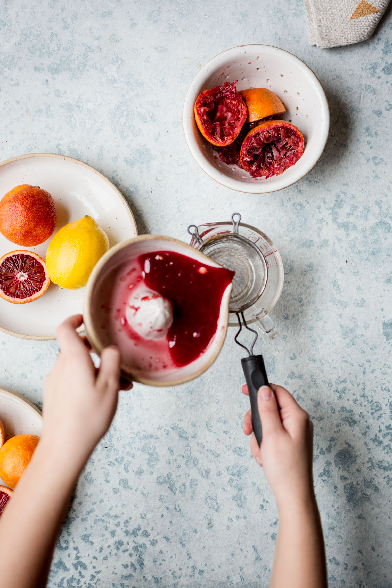 pouring blood orange juice through a sieve