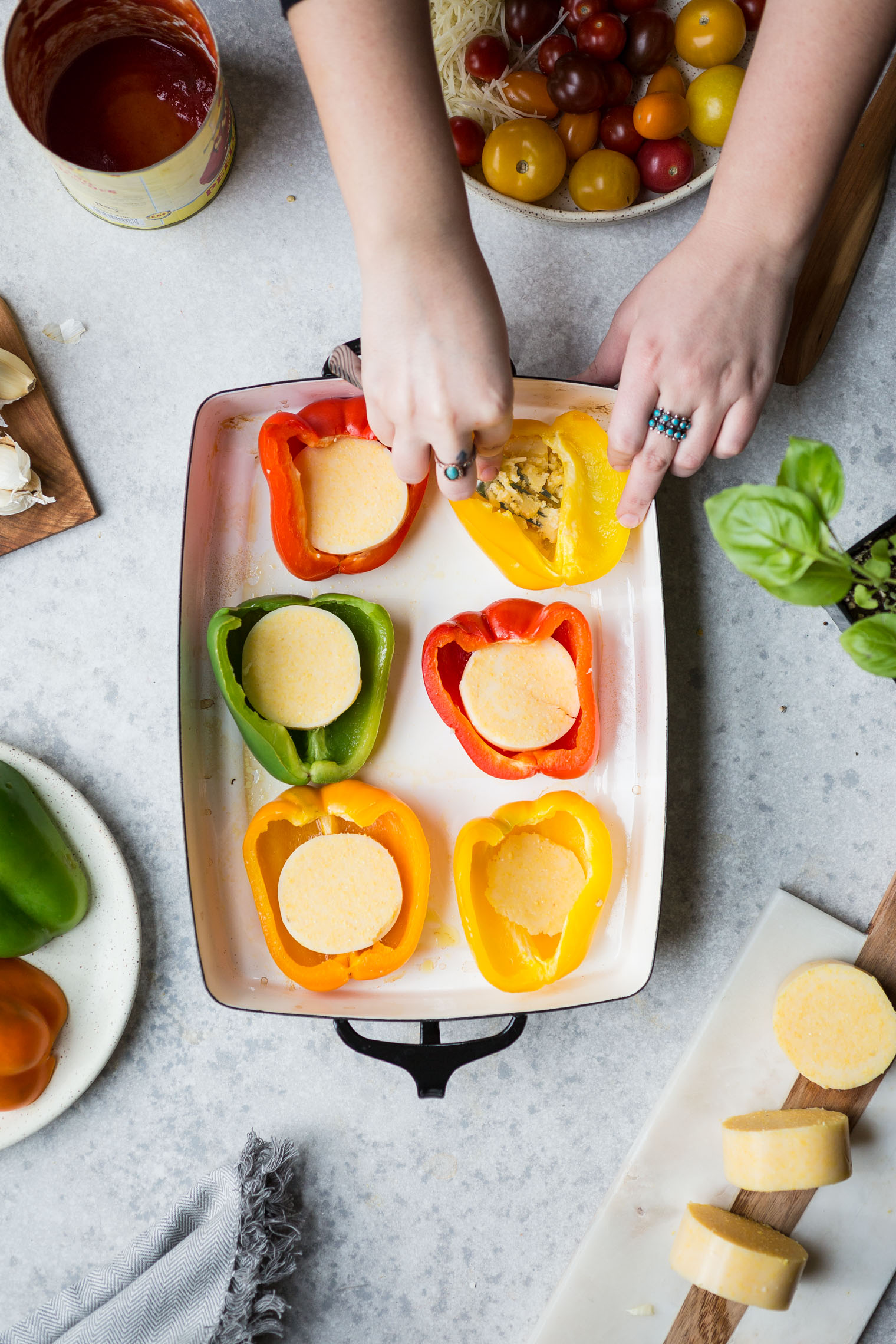 smashing polenta in the bottom of bell pepper halves resting in baking dish