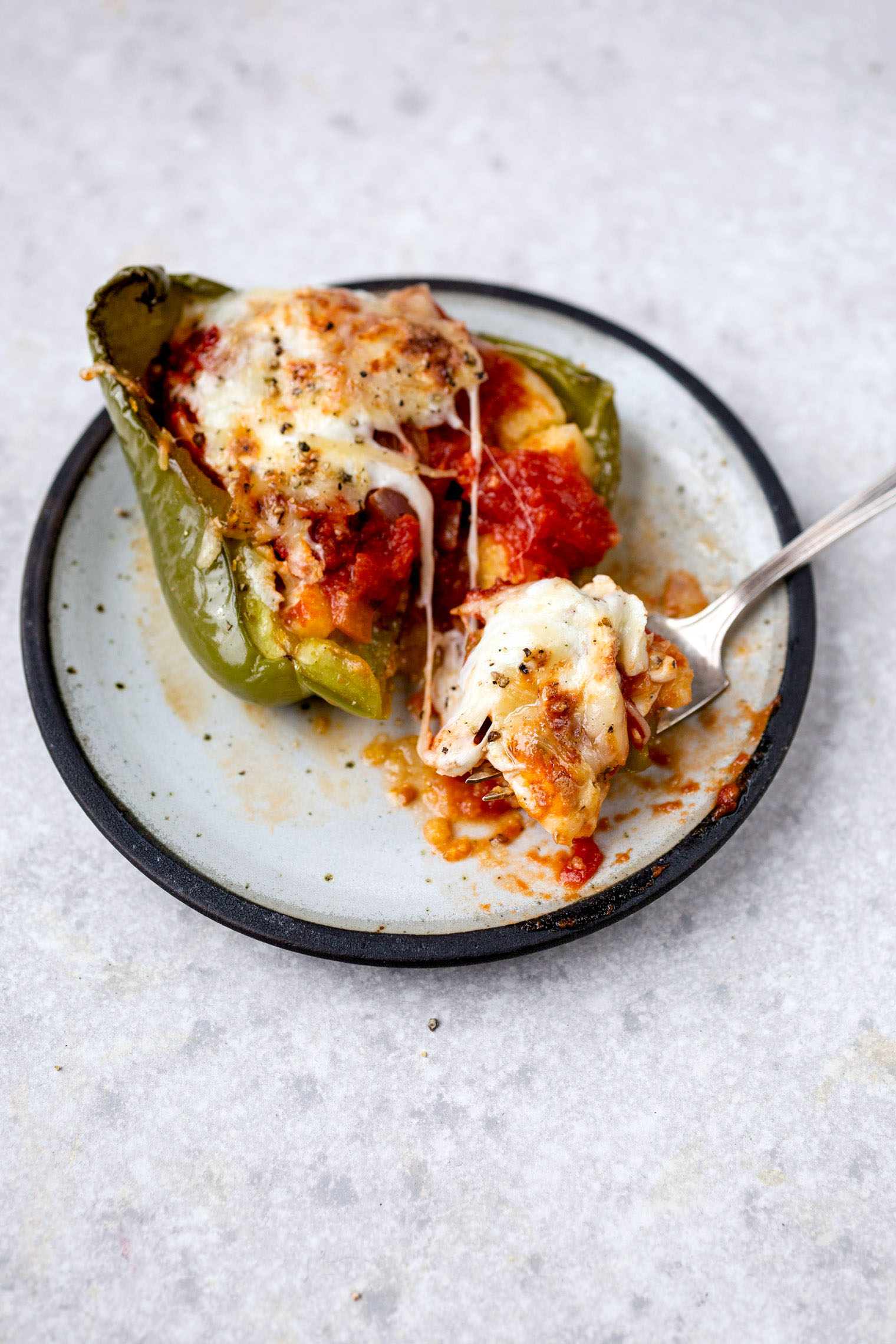 pizza stuffed bell pepper on white plate with fork