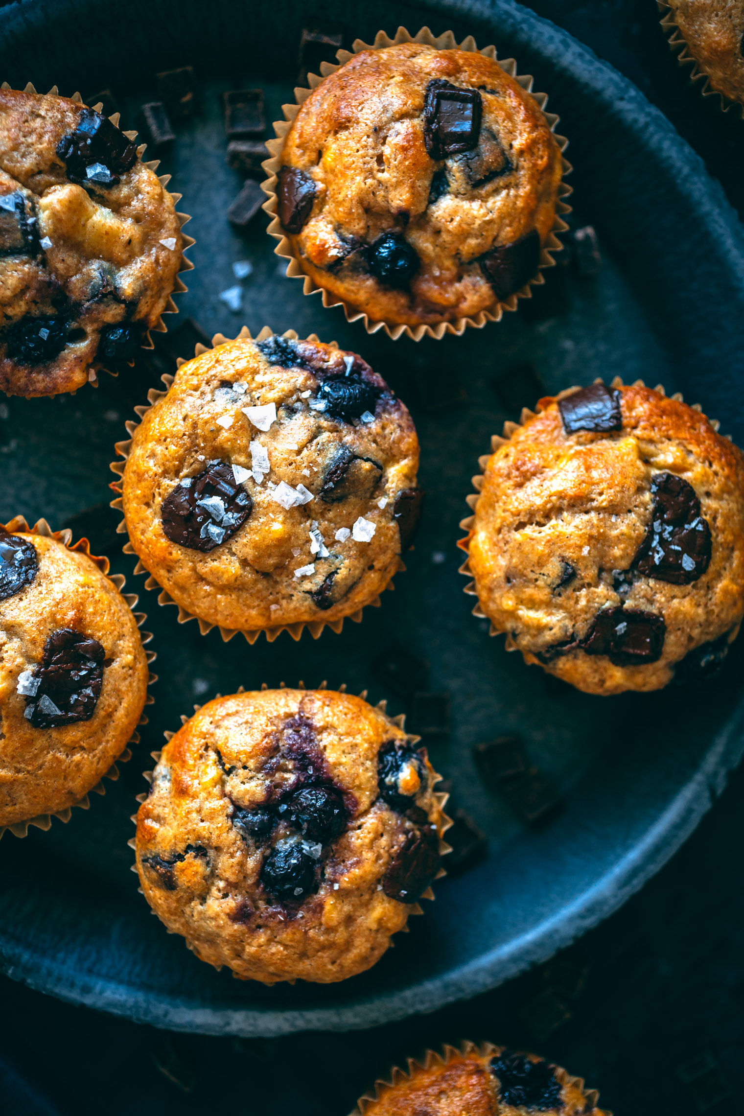 banana blueberry chocolate chip muffins on dark pie plate