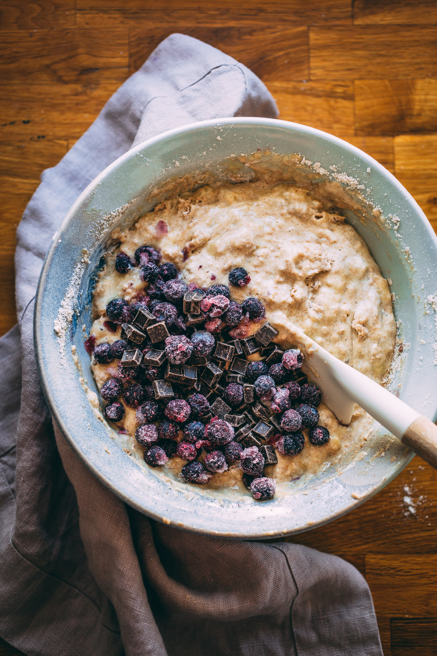 stirring together chocolate chip banana blueberry muffin batter