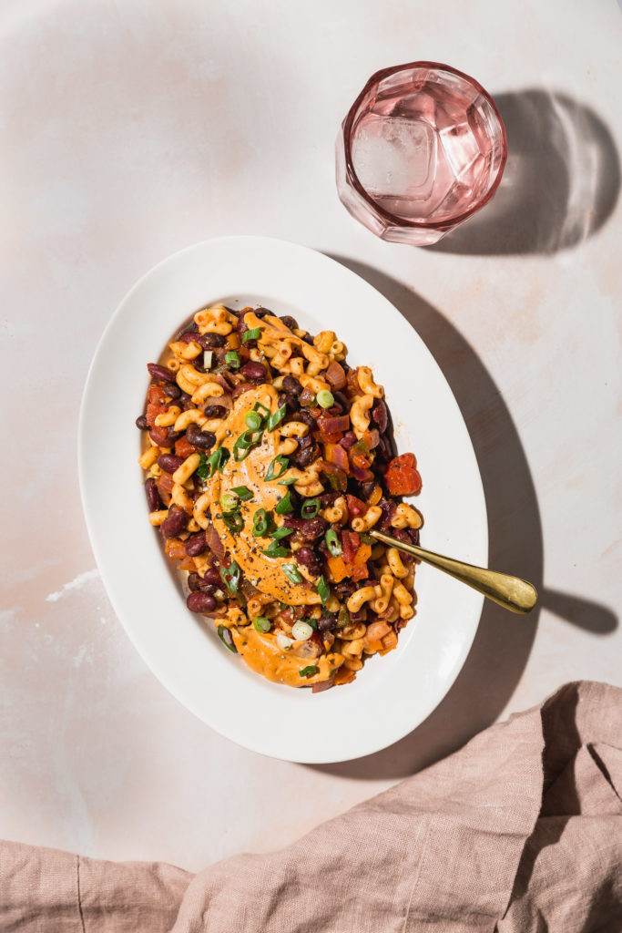 Vegan Chili Mac in serving platter next to linen towel and glass of water