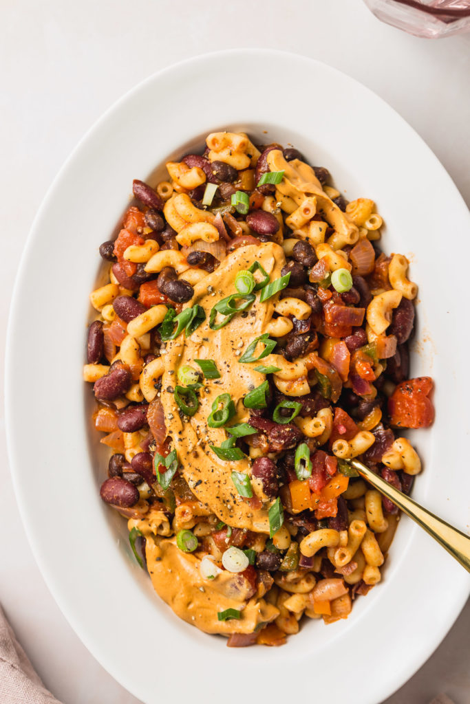 Vegan Chili Mac on white serving platter with gold spoon sticking out