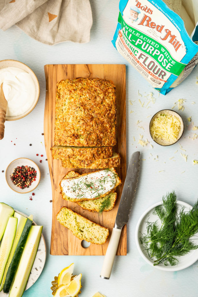 sliced loaf of Savory Zucchini Bread on wood cutting board