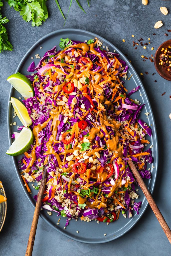 thai quinoa salad topped with peanut butter salad dressing on gray serving platter
