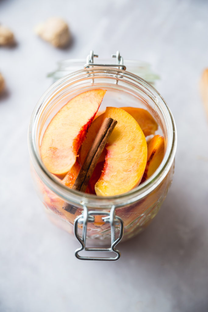 fresh peaches and cinnamon stick in glass jar to be pickled