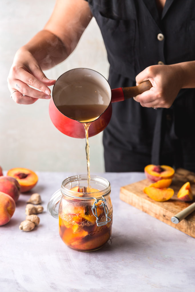pouring pickling liquid over fresh peaches in jar