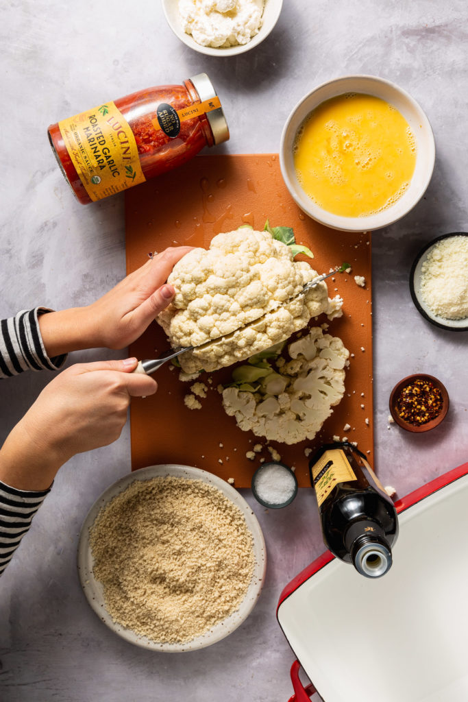 woman cutting head of cauliflower into a steak 