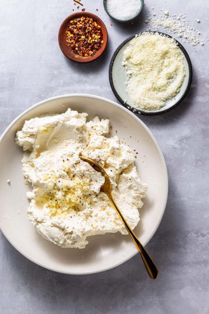 ricotta cheese mixture in white bowl with spoon sticking out