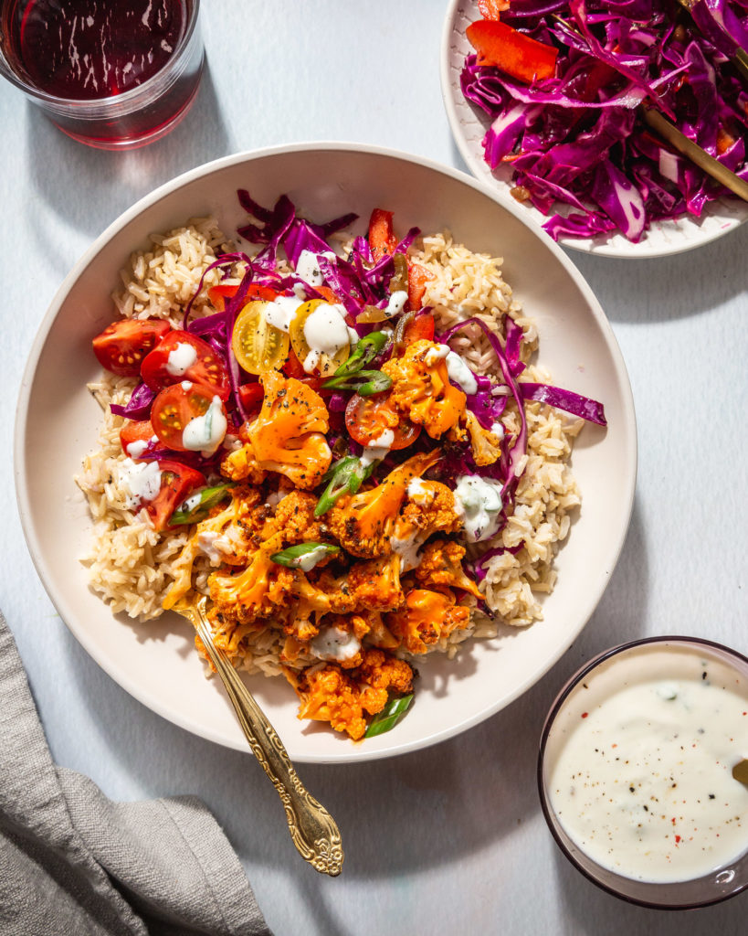 overhead view of baked Buffalo Cauliflower Bowl drizzle with greek yogurt ranch dressing