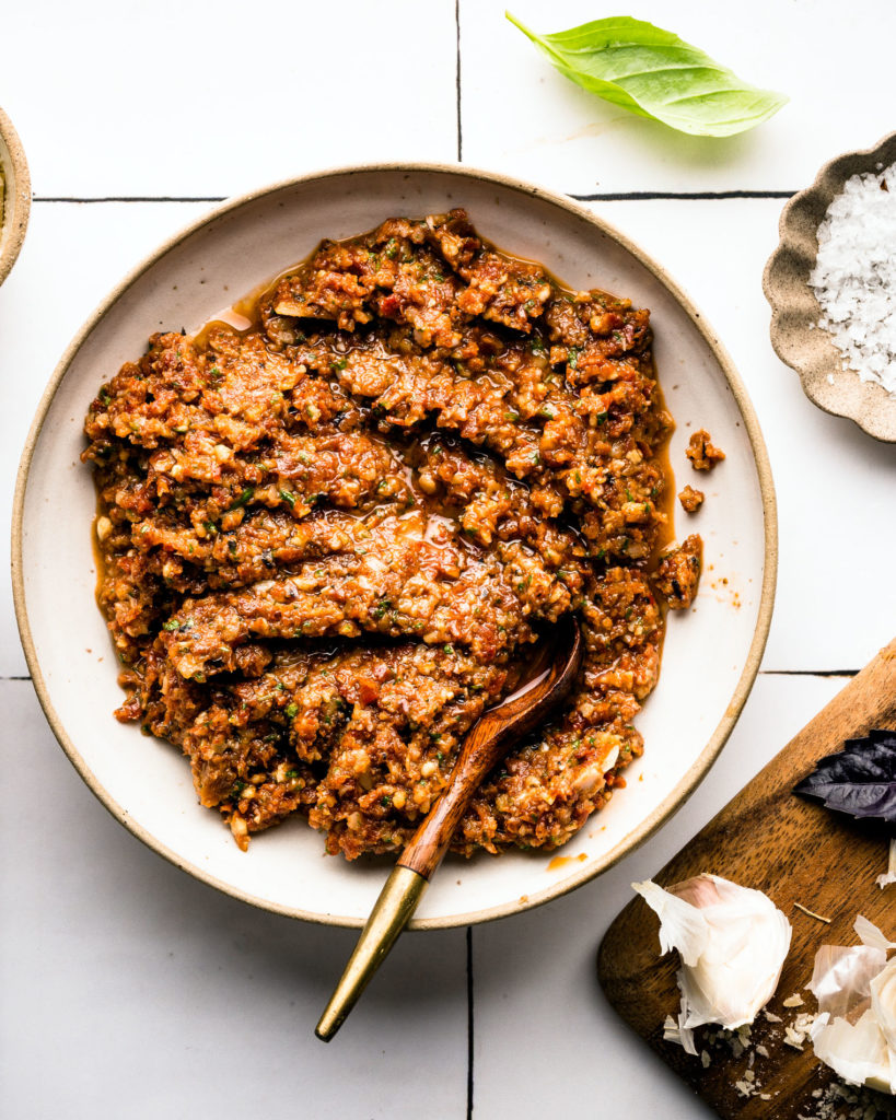 Sun Dried Tomato Pesto on white plate with wood spoon