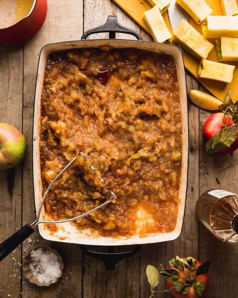 overhead of cooked apples being smashed into a butter