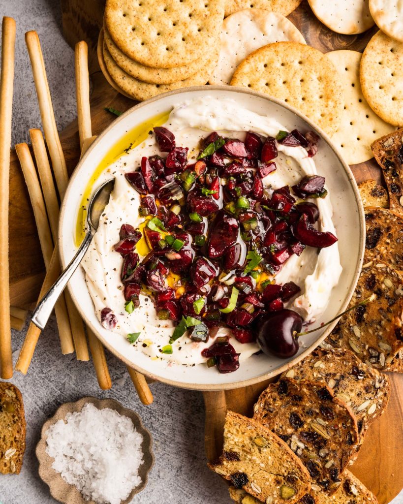 Cherry Jalapeño Dip with whipped goat cheese in a bowl with crackers around it