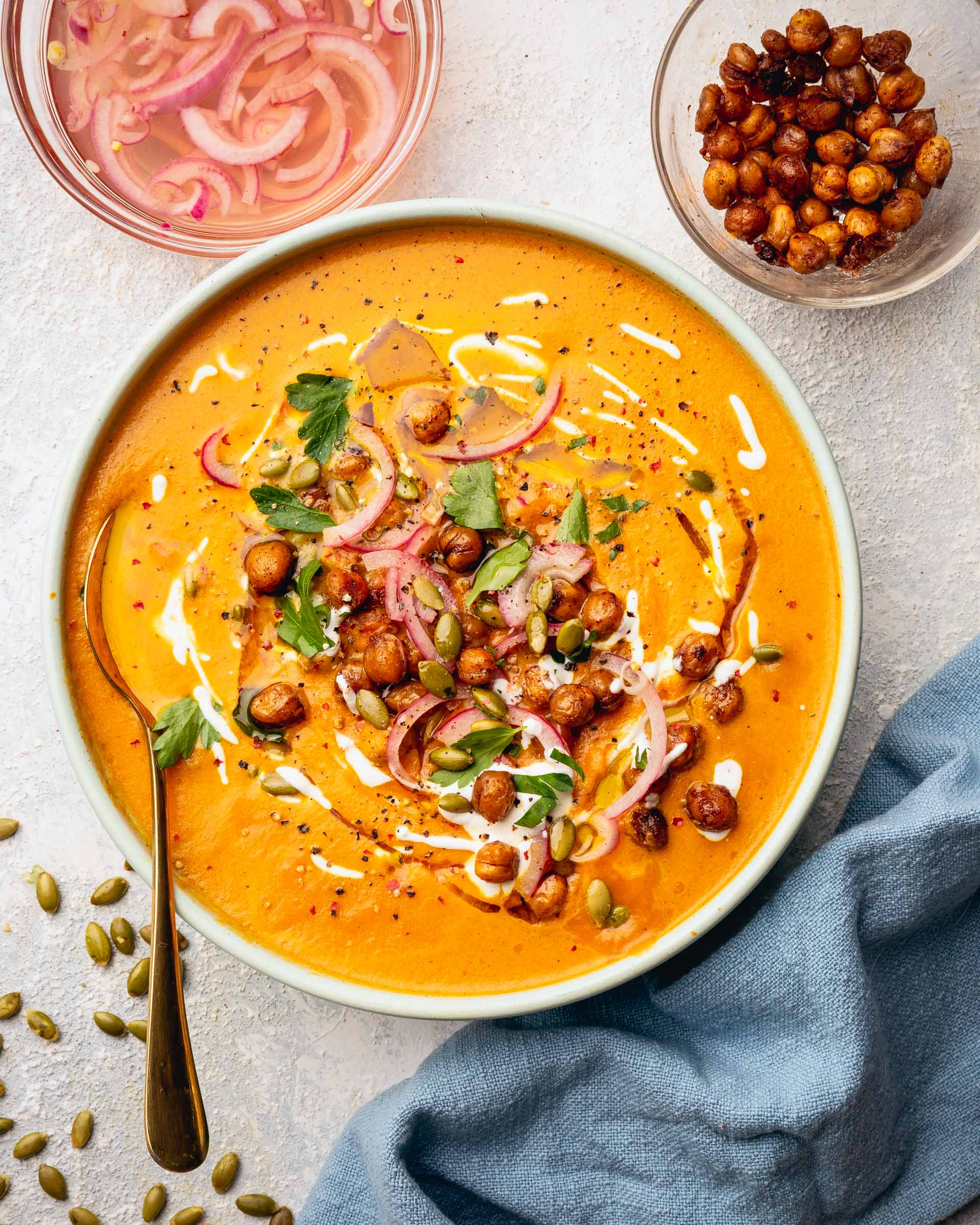 Curried Carrot Soup with Maple Roasted Chickpeas soup on table with toppings